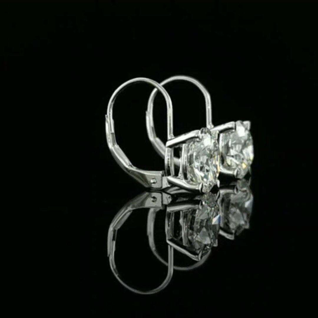May include: A pair of gold hoop earrings with a large, clear, round gemstone in the center of each hoop.