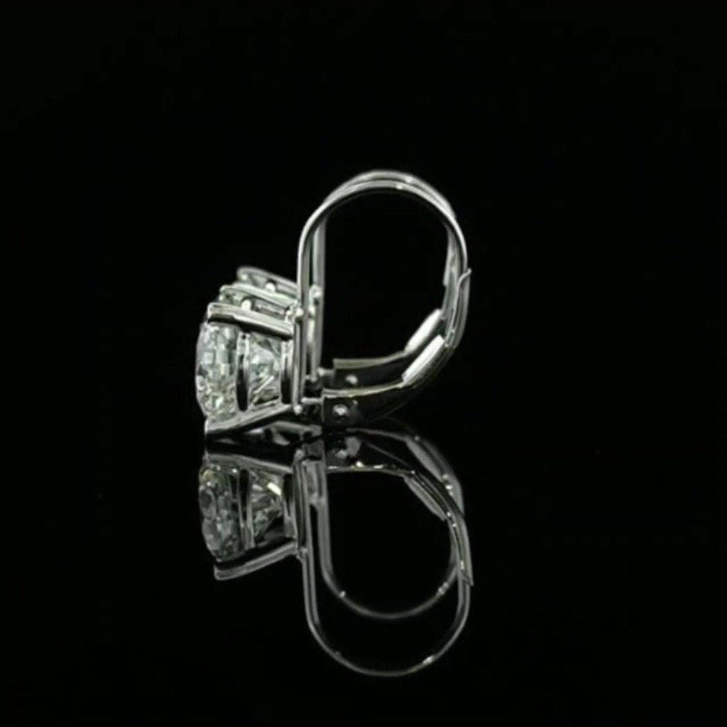 May include: A pair of gold earrings with three round diamonds. The earrings have a hinged post and a push-back closure.