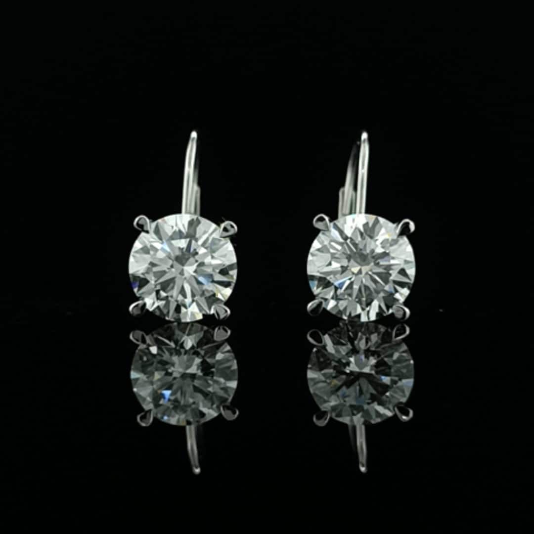 May include: Two gold dangle earrings with a round, clear, sparkling stone in the center of each earring.