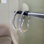 May include: Two gold hoop earrings with a row of clear diamonds around the outside of each hoop.