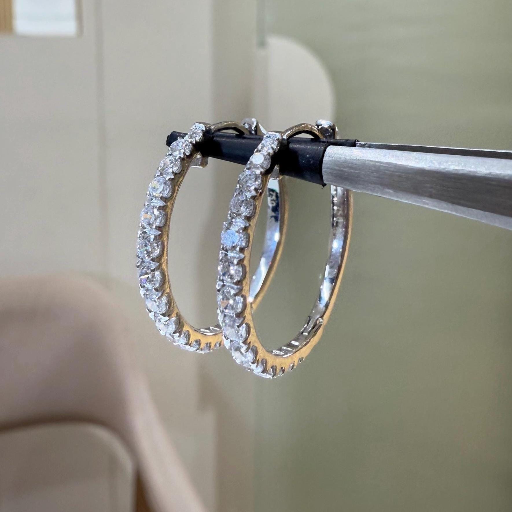 May include: Two gold hoop earrings with a row of clear diamonds around the outside of each hoop.