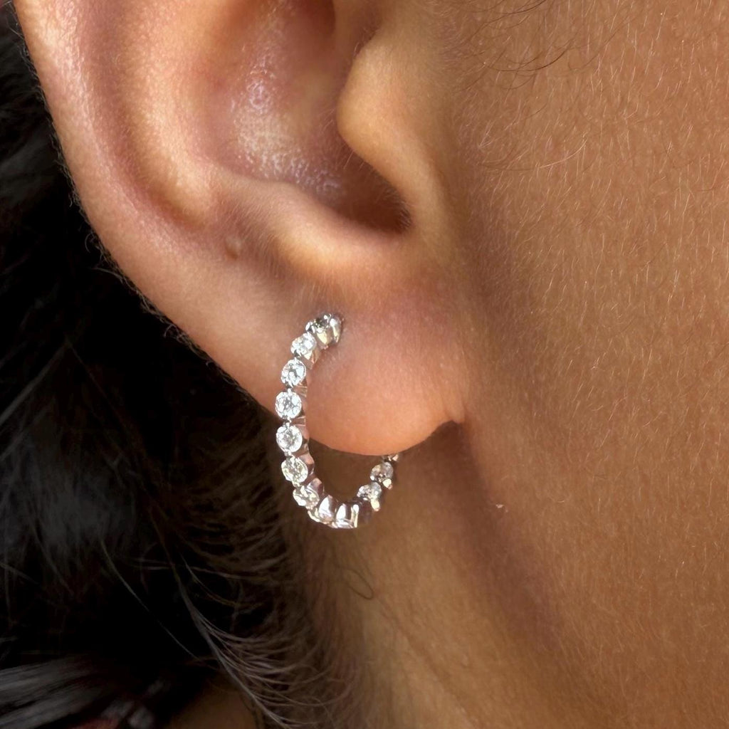 May include: gold hoop earrings with a row of small, clear lab Grown Diamond stones around the edge of the hoop.