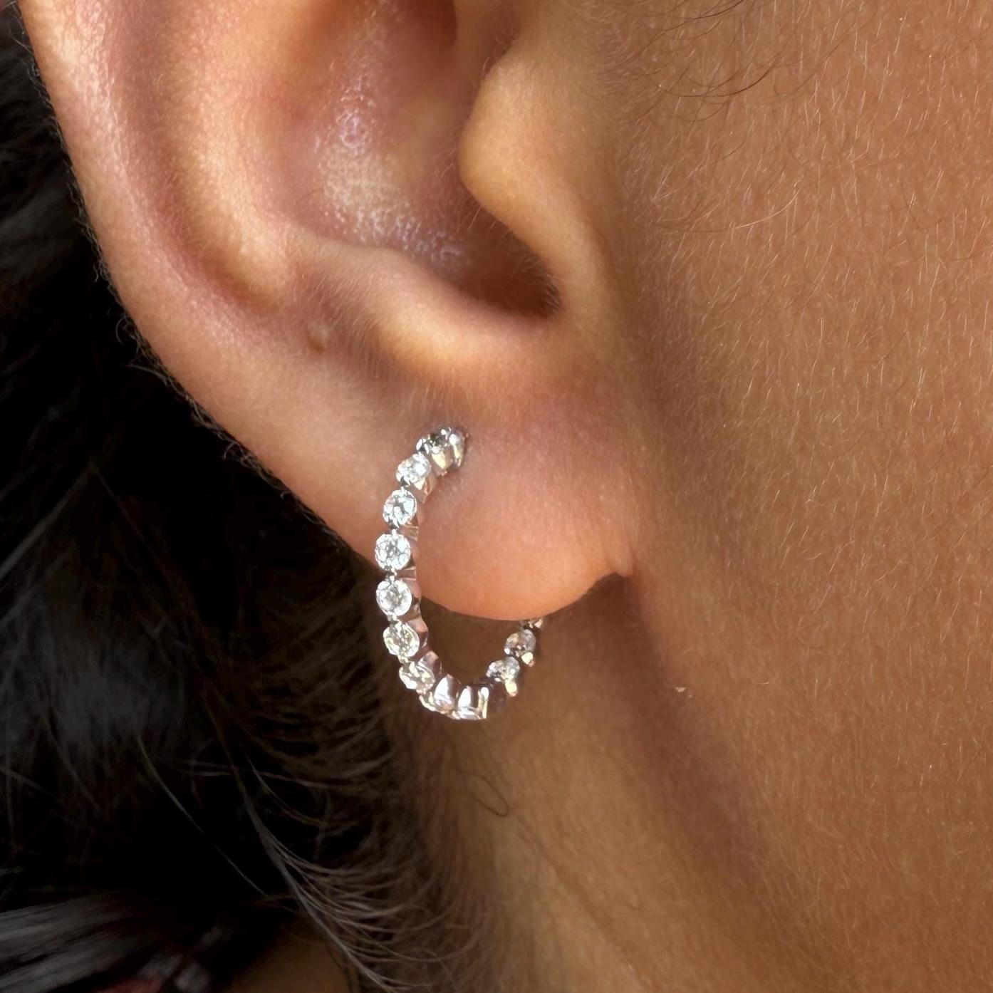 May include: gold hoop earrings with a row of small, clear lab Grown Diamond stones around the edge of the hoop.