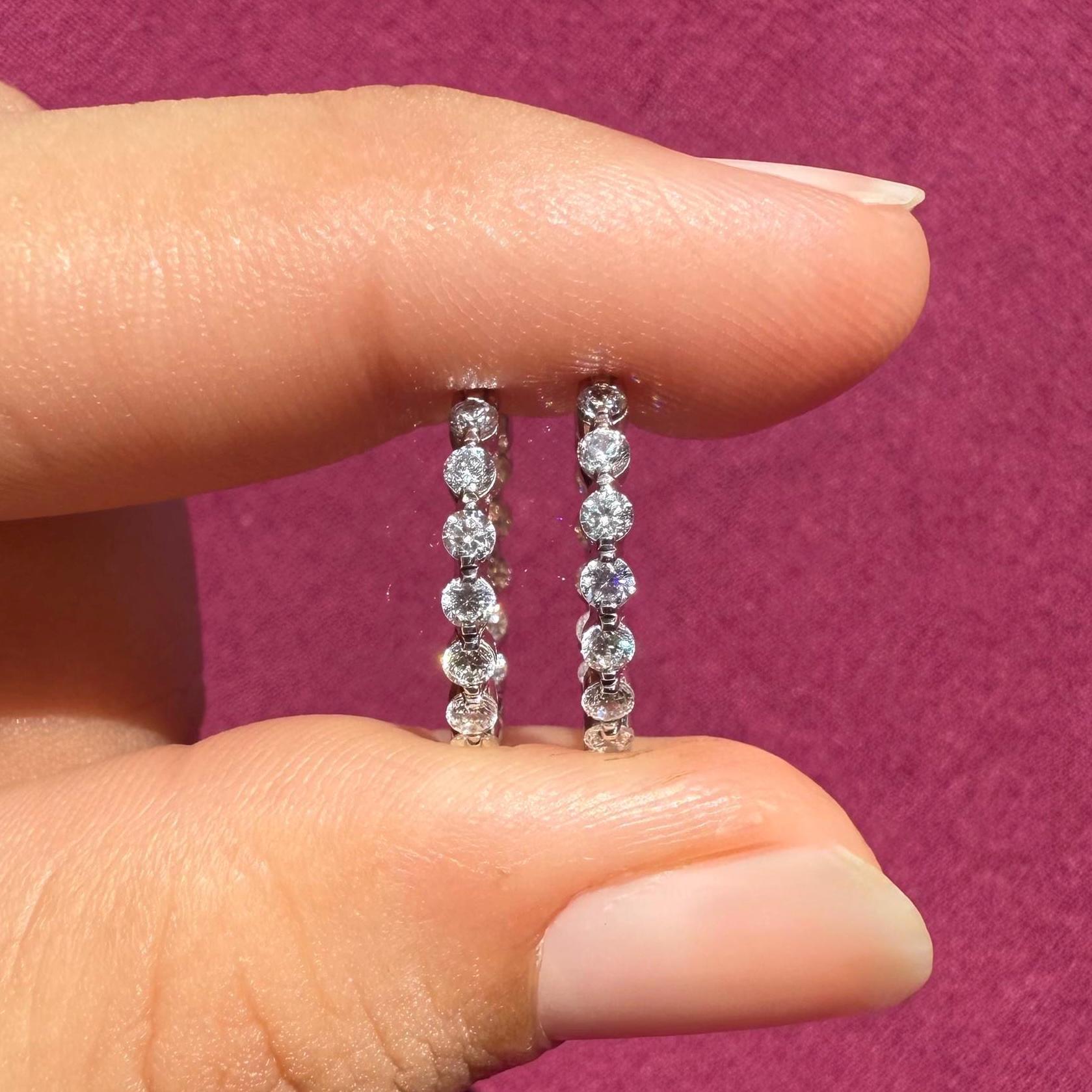 May include: Two pairs of small, round, gold hoop earrings with a row of clear, round diamonds set in each hoop.