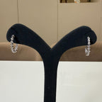 May include: Two white gold hoop earrings with a row of small, clear round stones set in the metal. The earrings are displayed on a black stand.