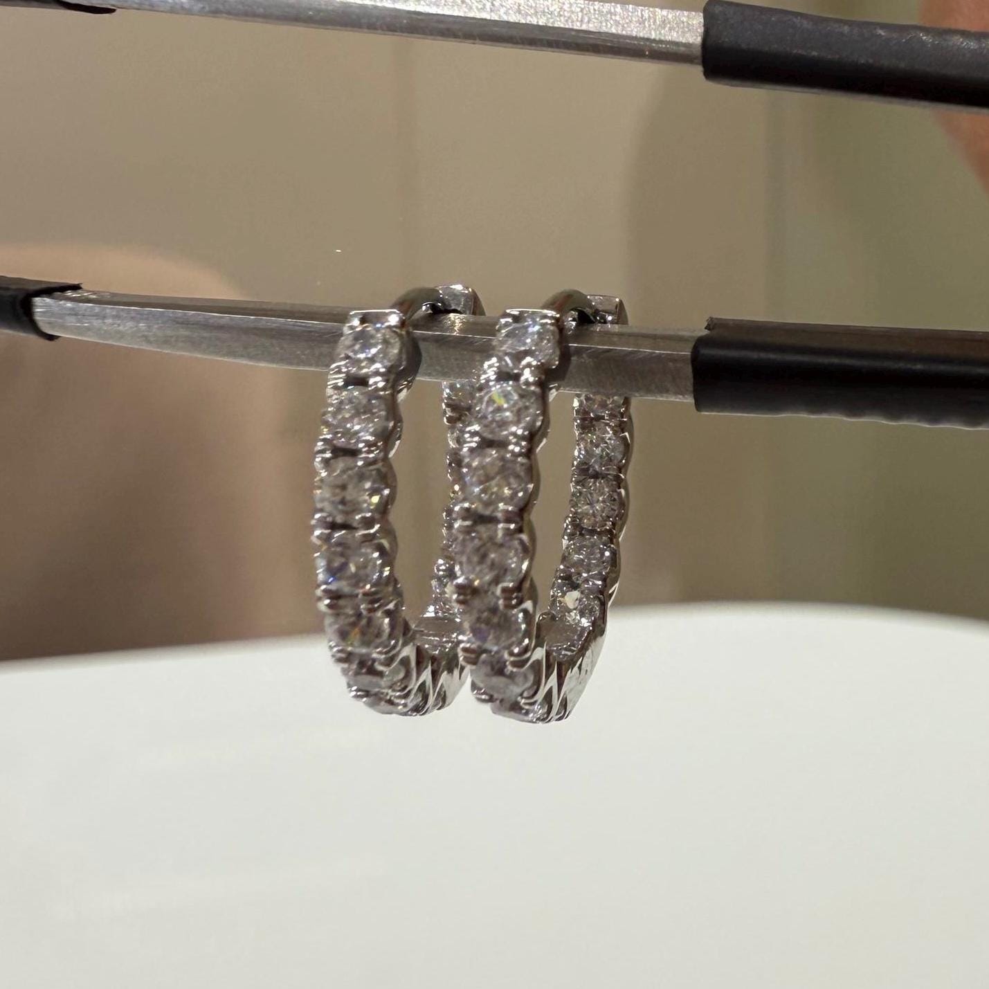 May include: Two gold hoop earrings with a row of small, clear, round diamond around the outside of each hoop.