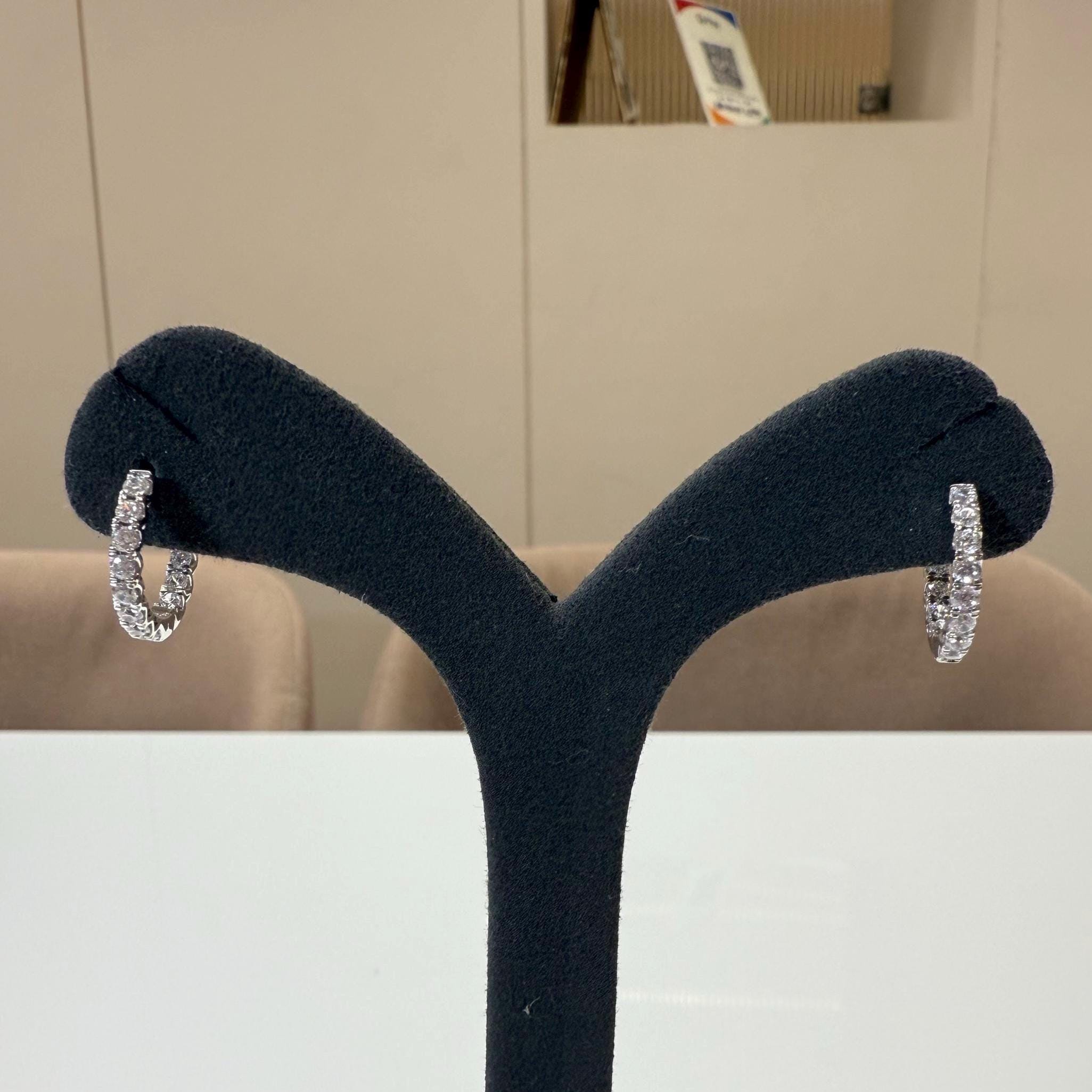 May include: A pair of gold hoop earrings with a row of small clear diamonds around the outside of each hoop.