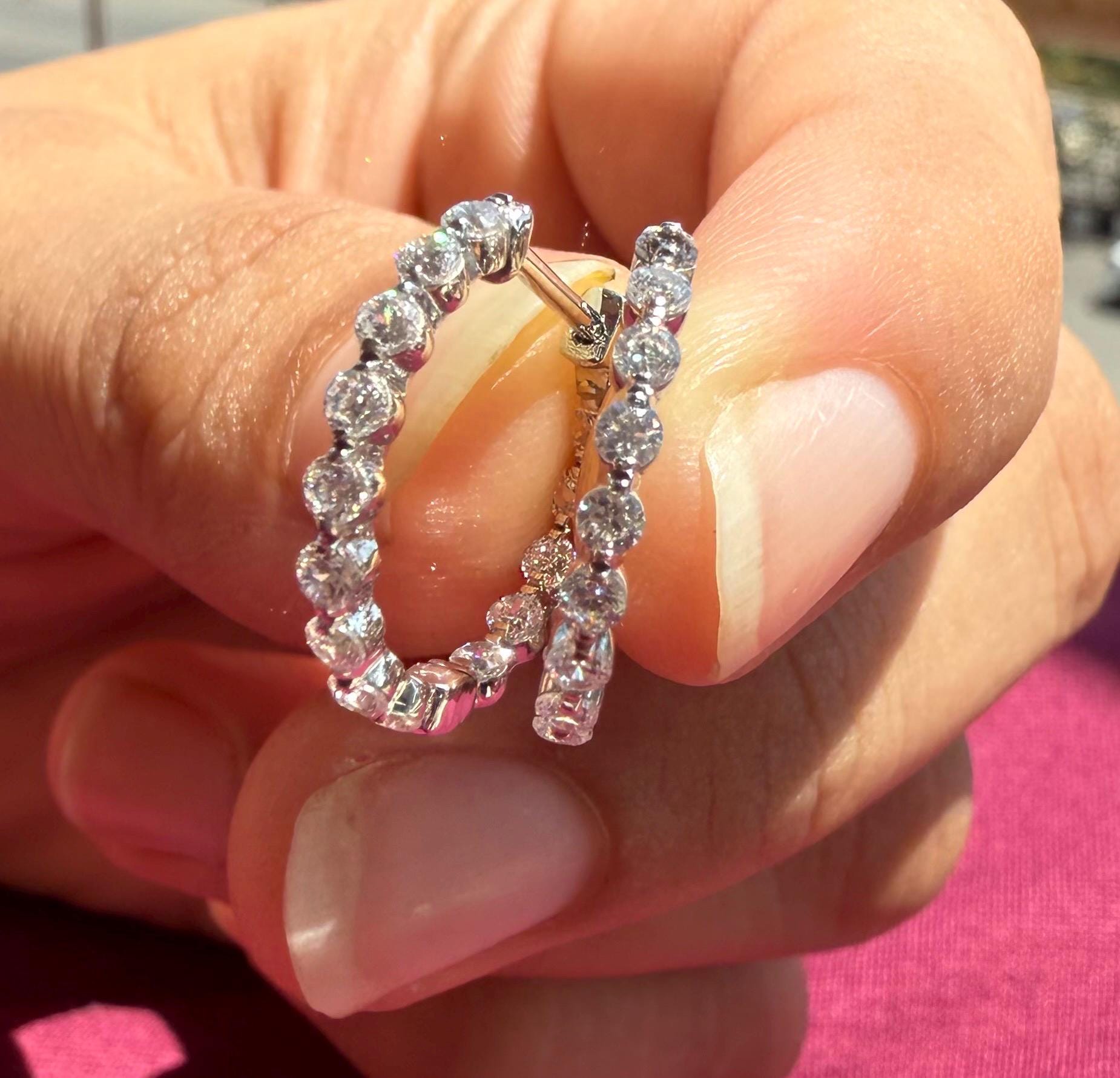 May include: Two gold hoop earrings with a row of small, clear diamonds around the outside of each hoop.
