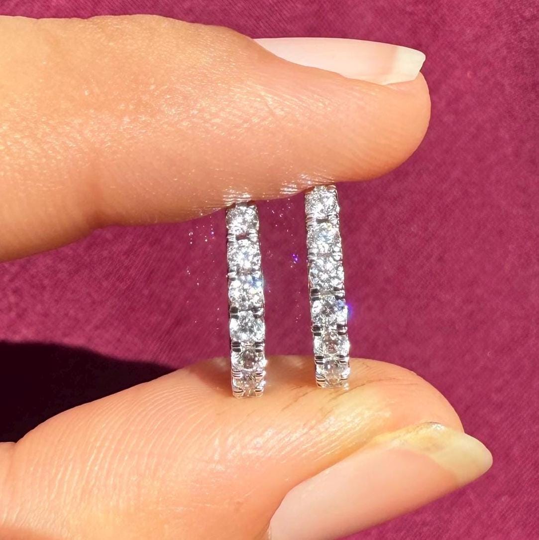 Two white Gold hoop earrings with a row of clear round diamonds stones around the entire hoop.