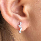 May include: A white gold earring with a curved design featuring five marquise-shaped clear stones.