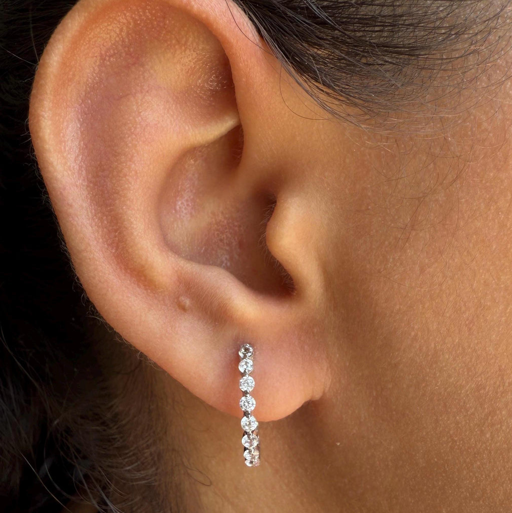 May include: A pair of white gold hoop earrings with a row of small, clear, round diamonds.