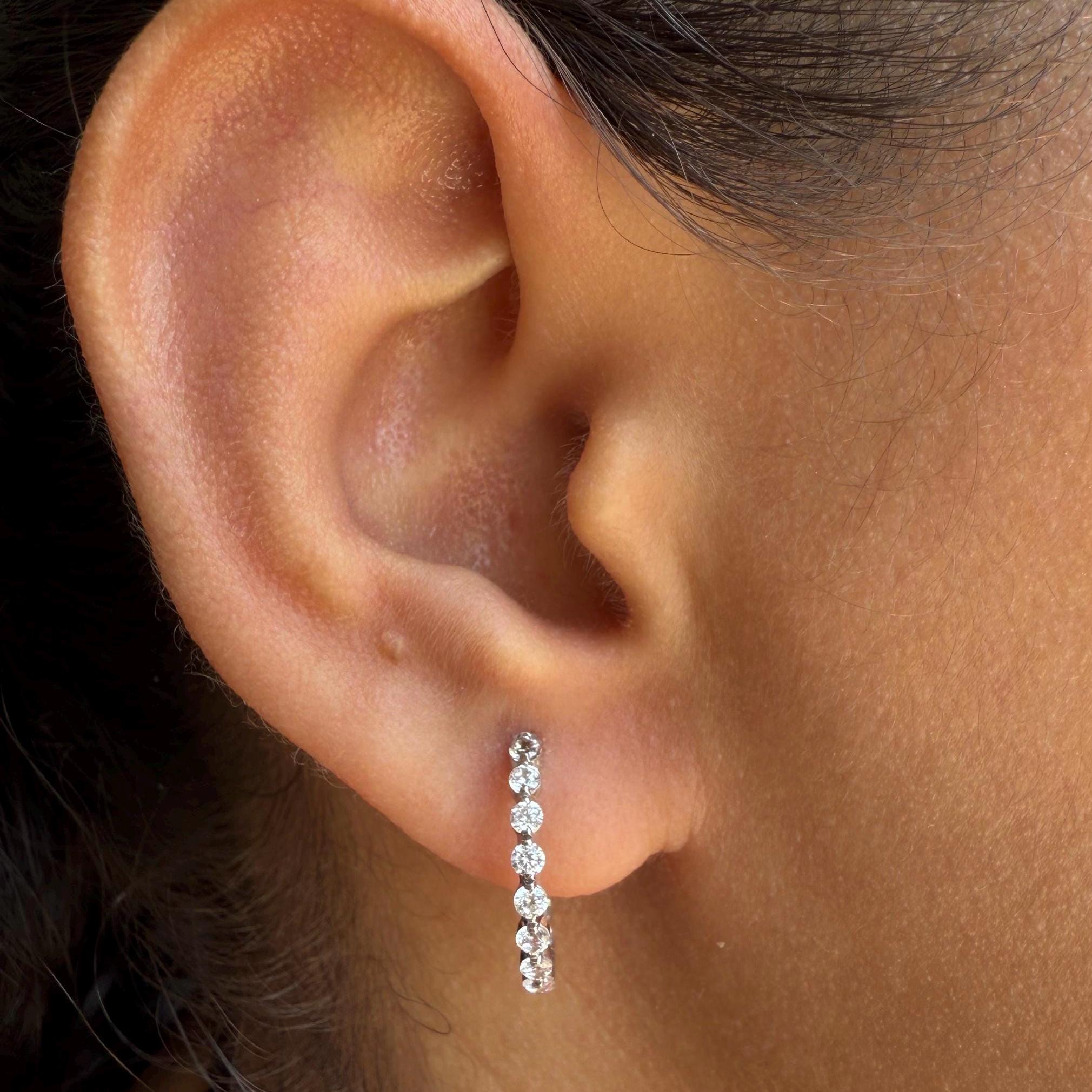 May include: A pair of white gold hoop earrings with a row of small, clear, round diamonds.