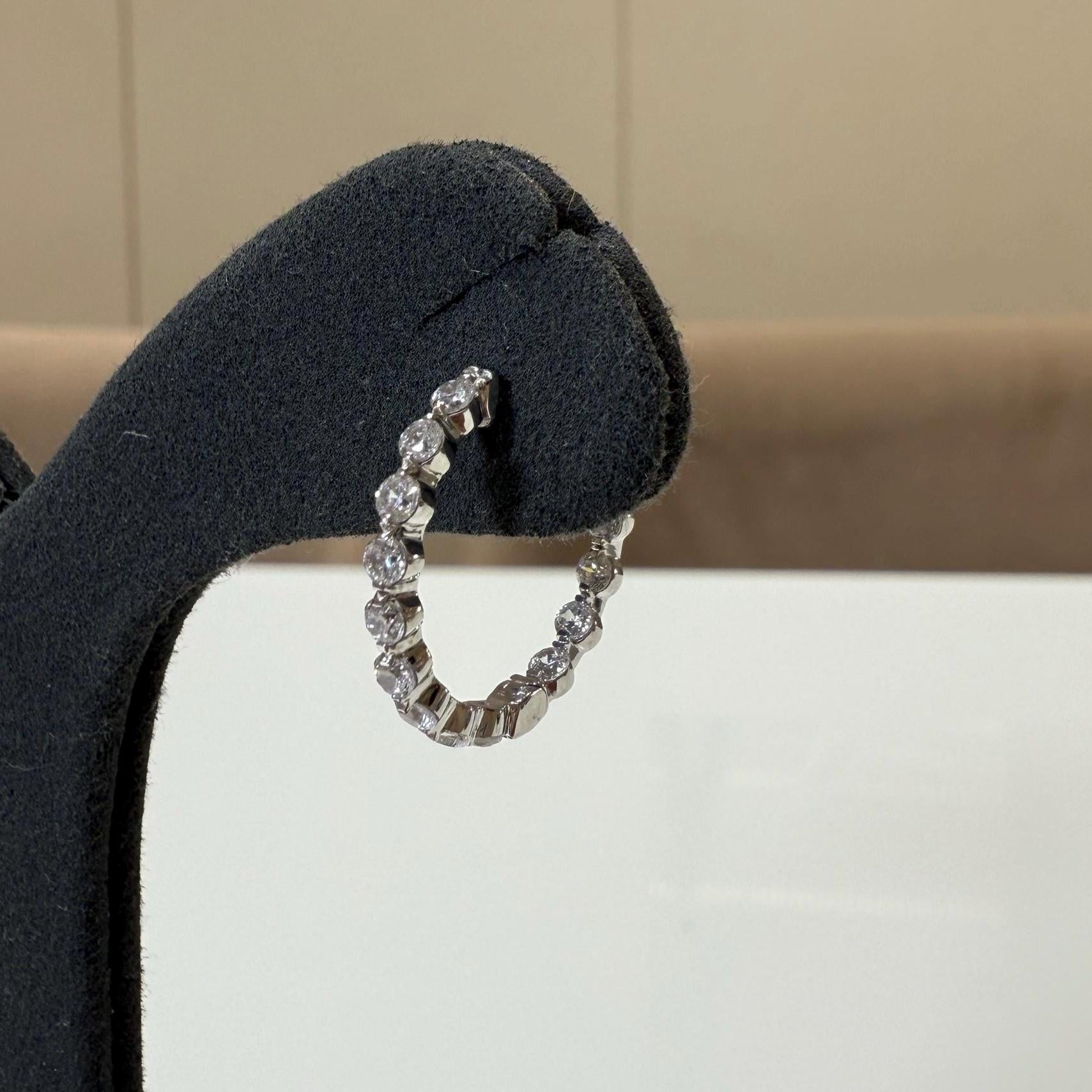 May include: A white gold hoop earring with a row of small, clear round Diamonds.
