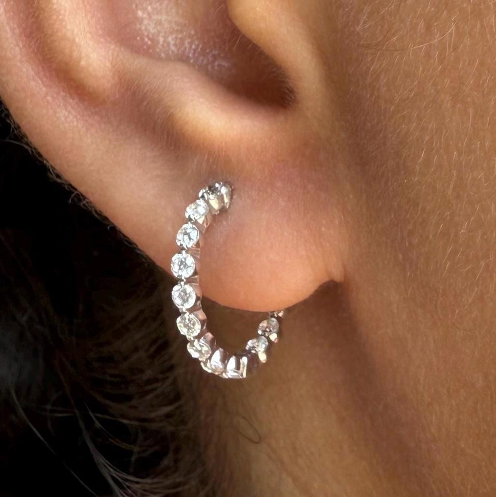 May include: A pair of gold hoop earrings with a row of small, clear Lab grown diamond around the hoop.