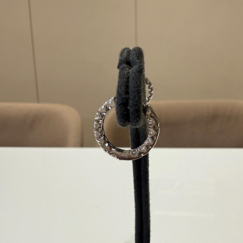 May include: gold hoop earrings with small clear stones set in the metal. The earrings are displayed on a black stand.