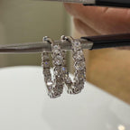 Two white Gold hoop earrings with a row of clear round diamonds stones around the entire hoop.